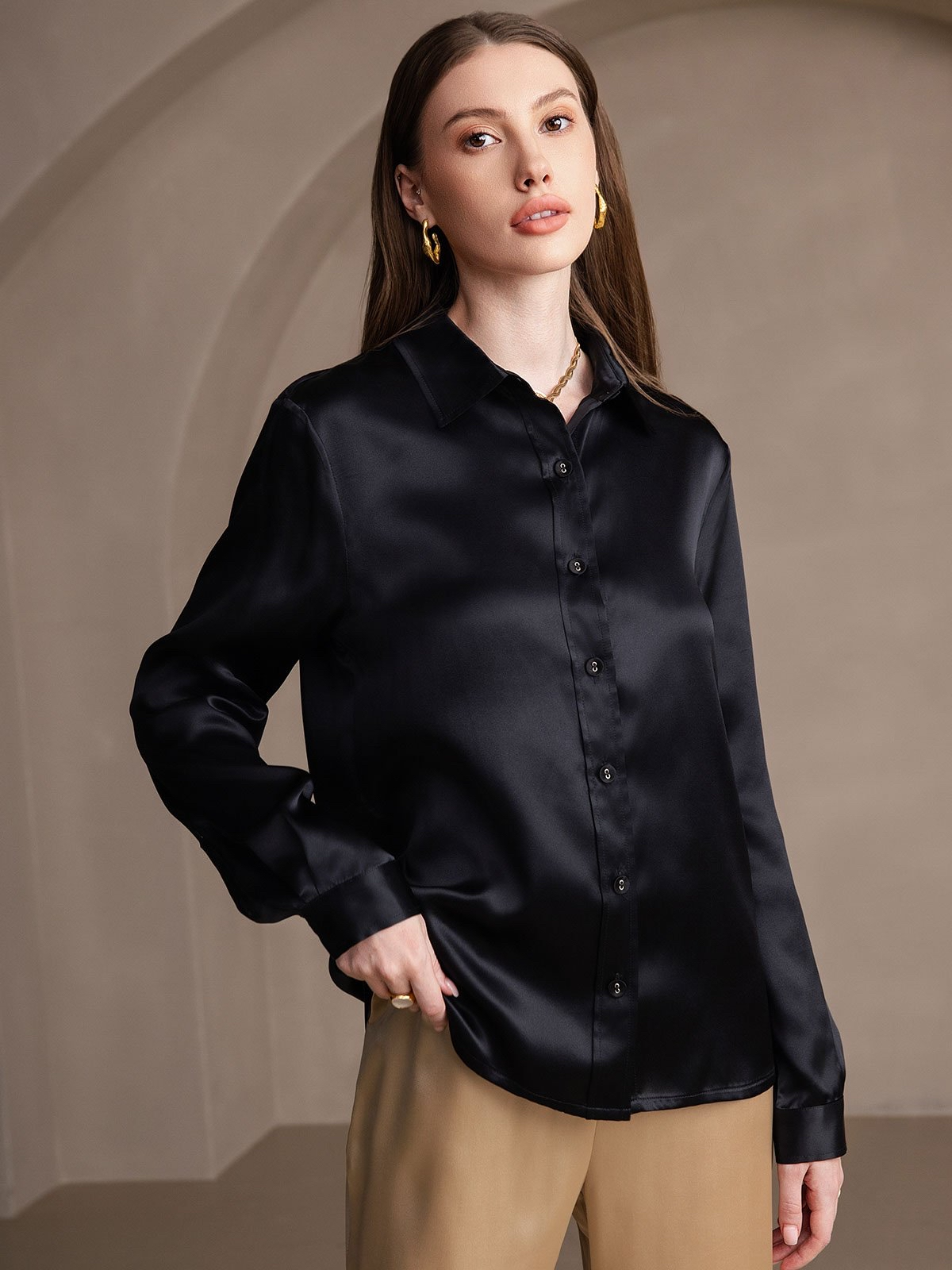 Woman wearing a black satin shirt against a beige background