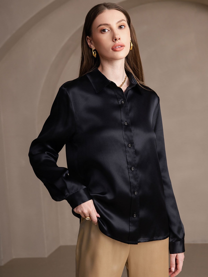 Woman wearing a black satin shirt against a beige background