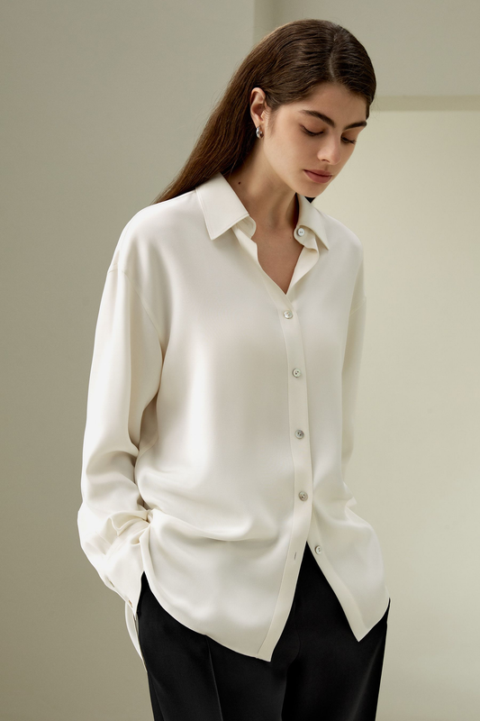 Woman wearing a white button-up shirt against a plain background
